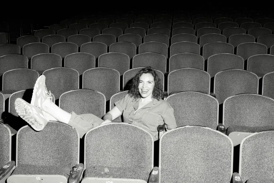 Beth lying across theater seats, black and white