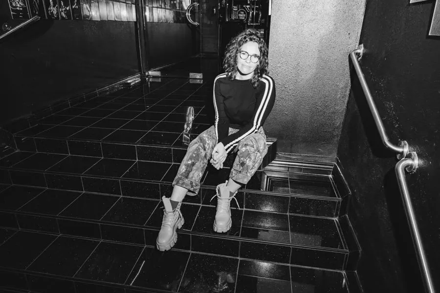 Beth sitting on black tiled stairs, black and white