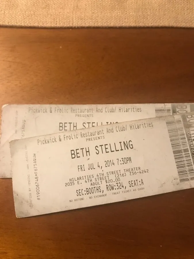 Two paper tickets for a Beth Stelling show on a wooden table