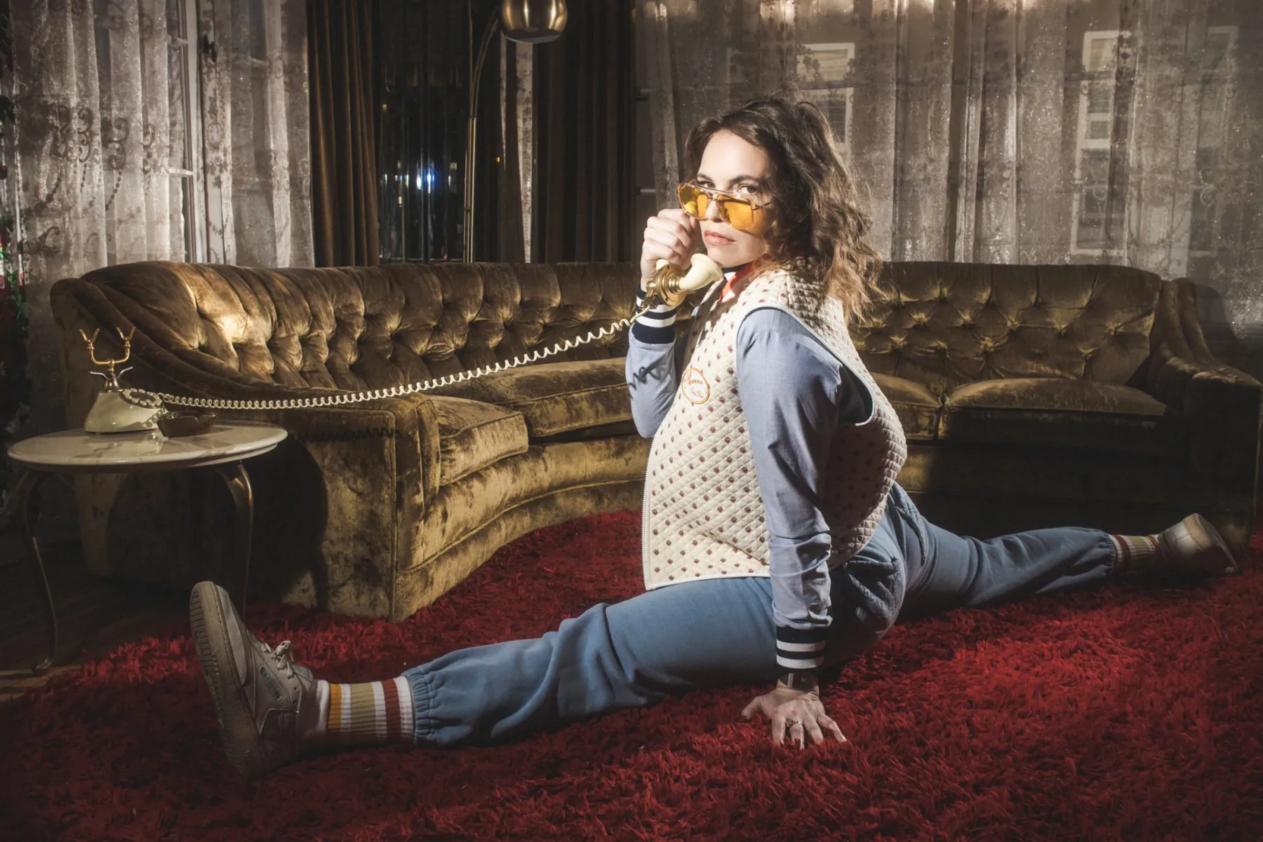Beth Stelling in a split on red shag carpet, holding a rotary phone