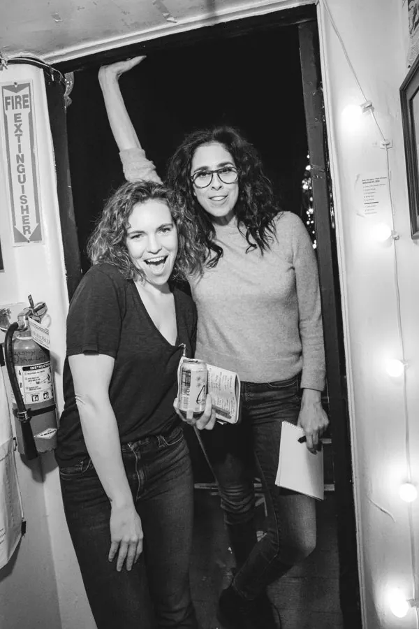 Beth and a friend laughing in a doorway, black and white