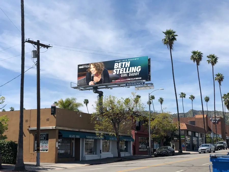 A Beth Stelling Girl Daddy billboard above a street lined with palm trees